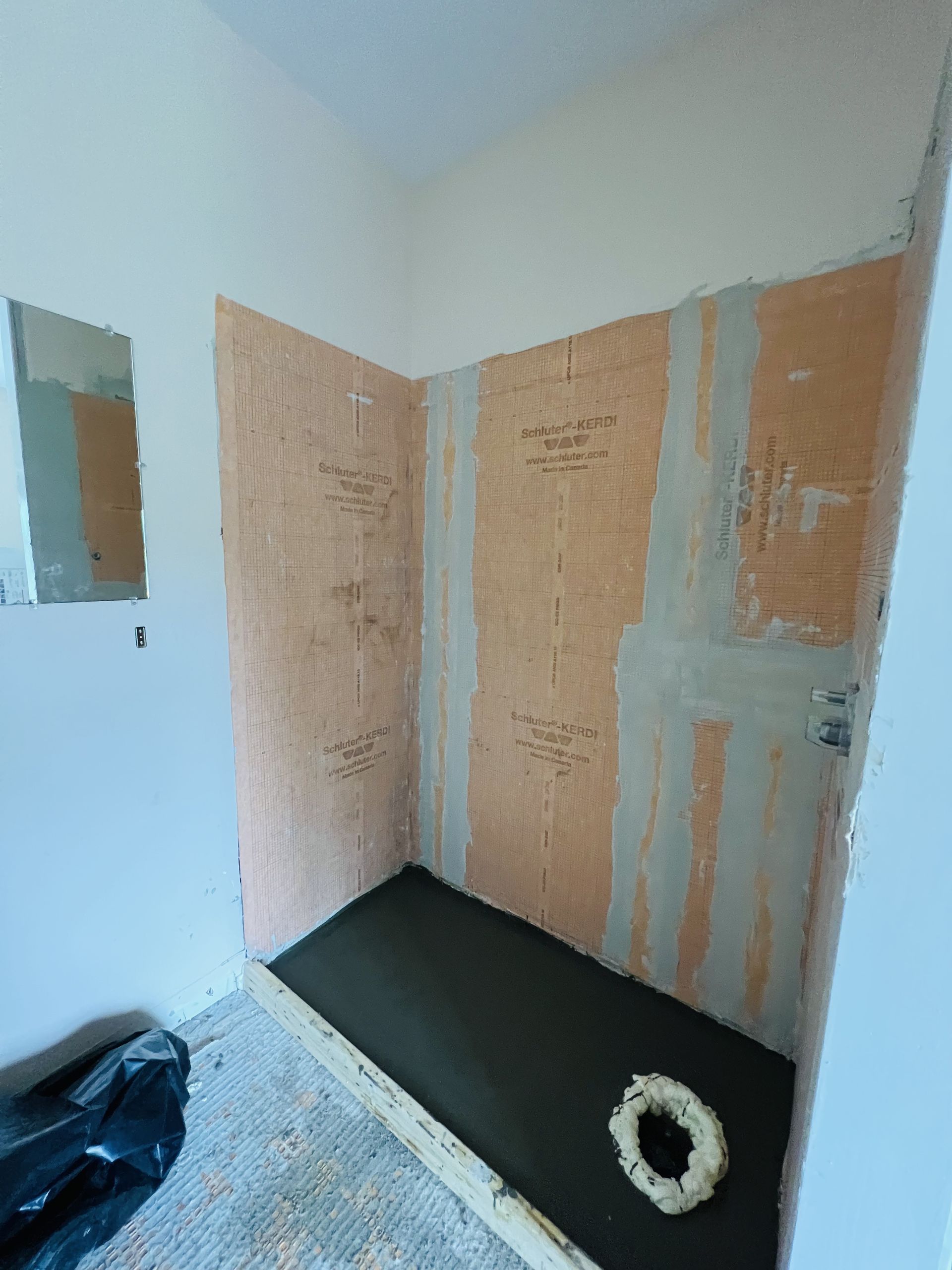 A bathroom under construction with a concrete floor and a wreath on the floor.