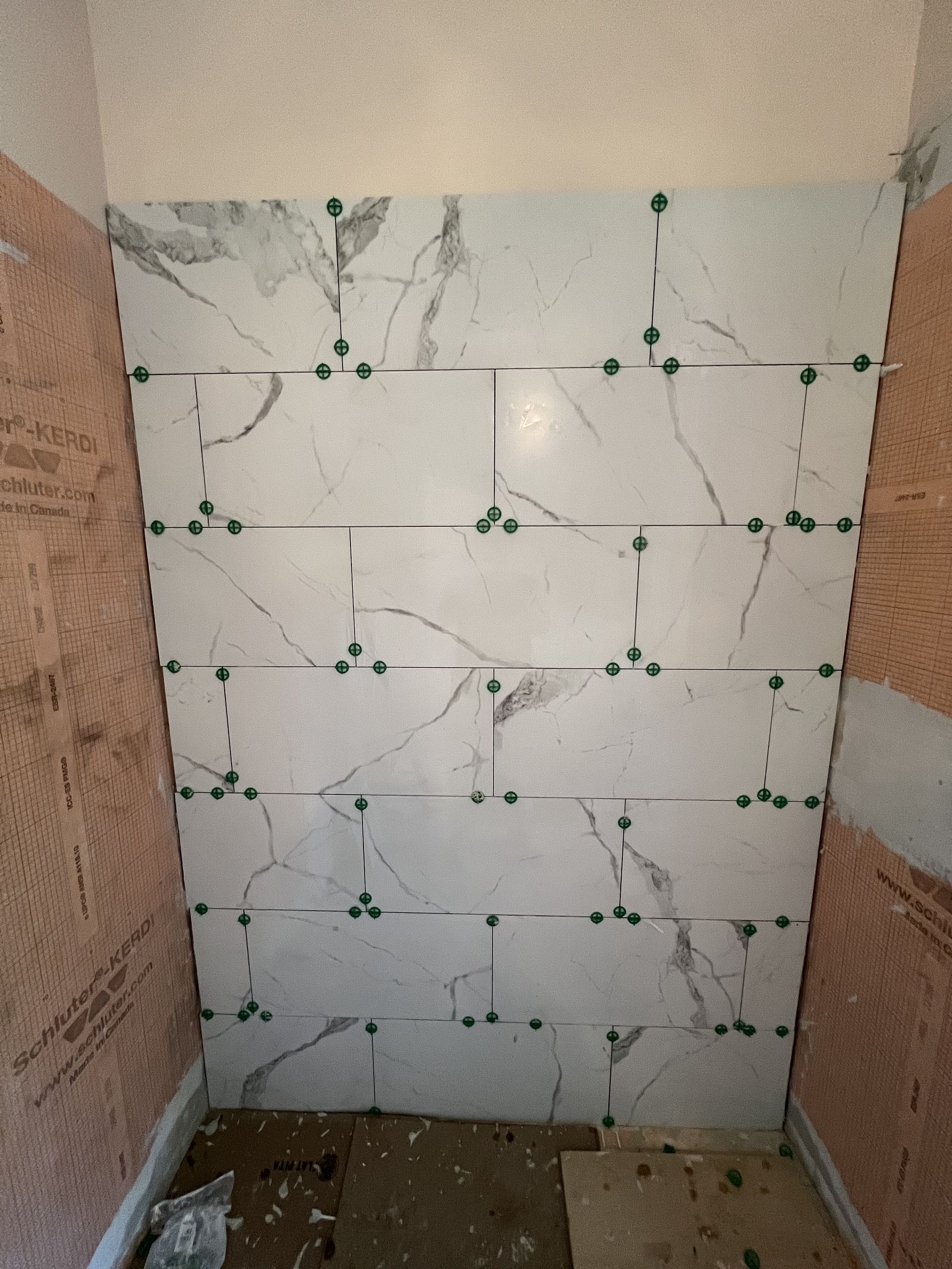 A bathroom with marble tiles being installed on the wall