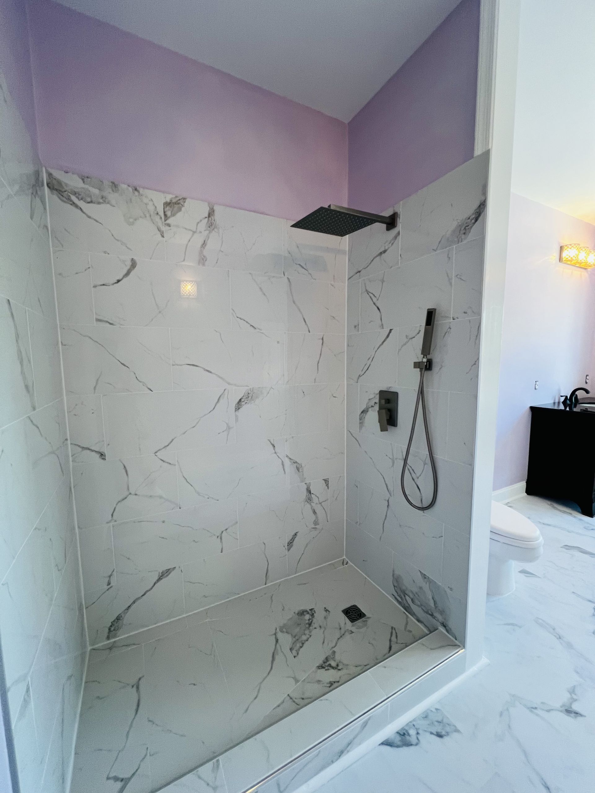 A bathroom with a walk in shower and a purple wall.