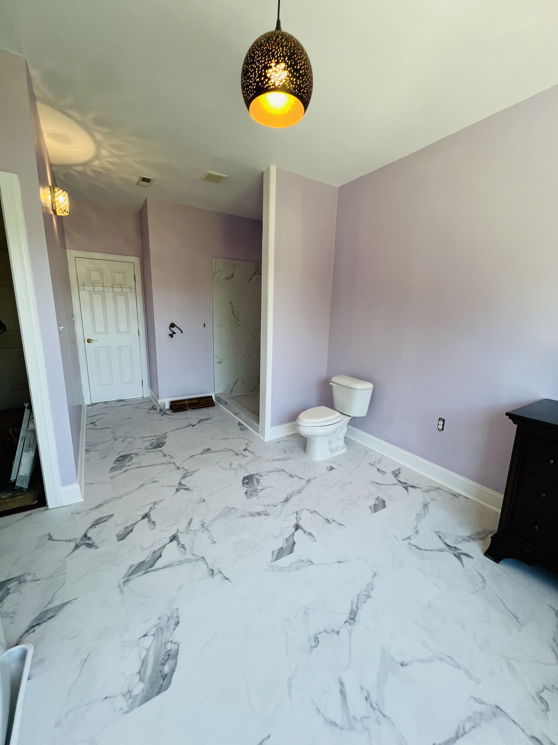 A bathroom with a toilet and a marble floor.