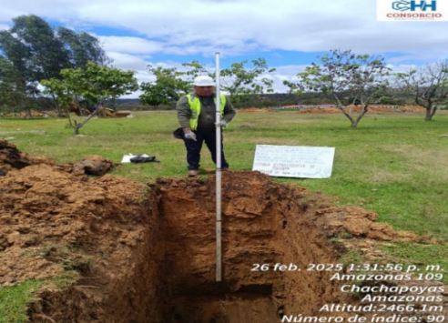 Un hombre está parado en un agujero en el suelo sosteniendo un poste.