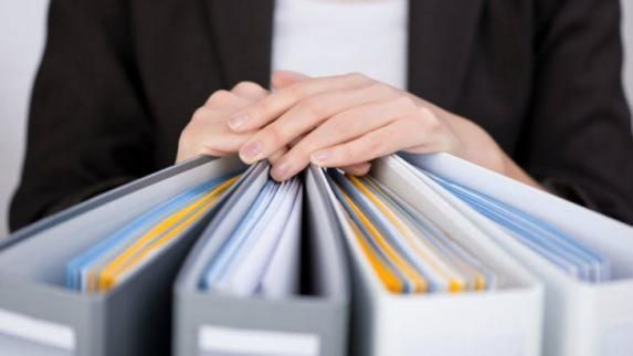 Una mujer sostiene una pila de carpetas en sus manos.