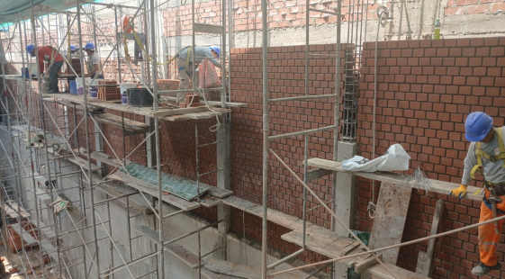 Un grupo de trabajadores de la construcción está trabajando en una pared de ladrillos.