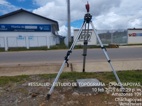 Un trípode está sentado al costado de la carretera frente a un edificio.