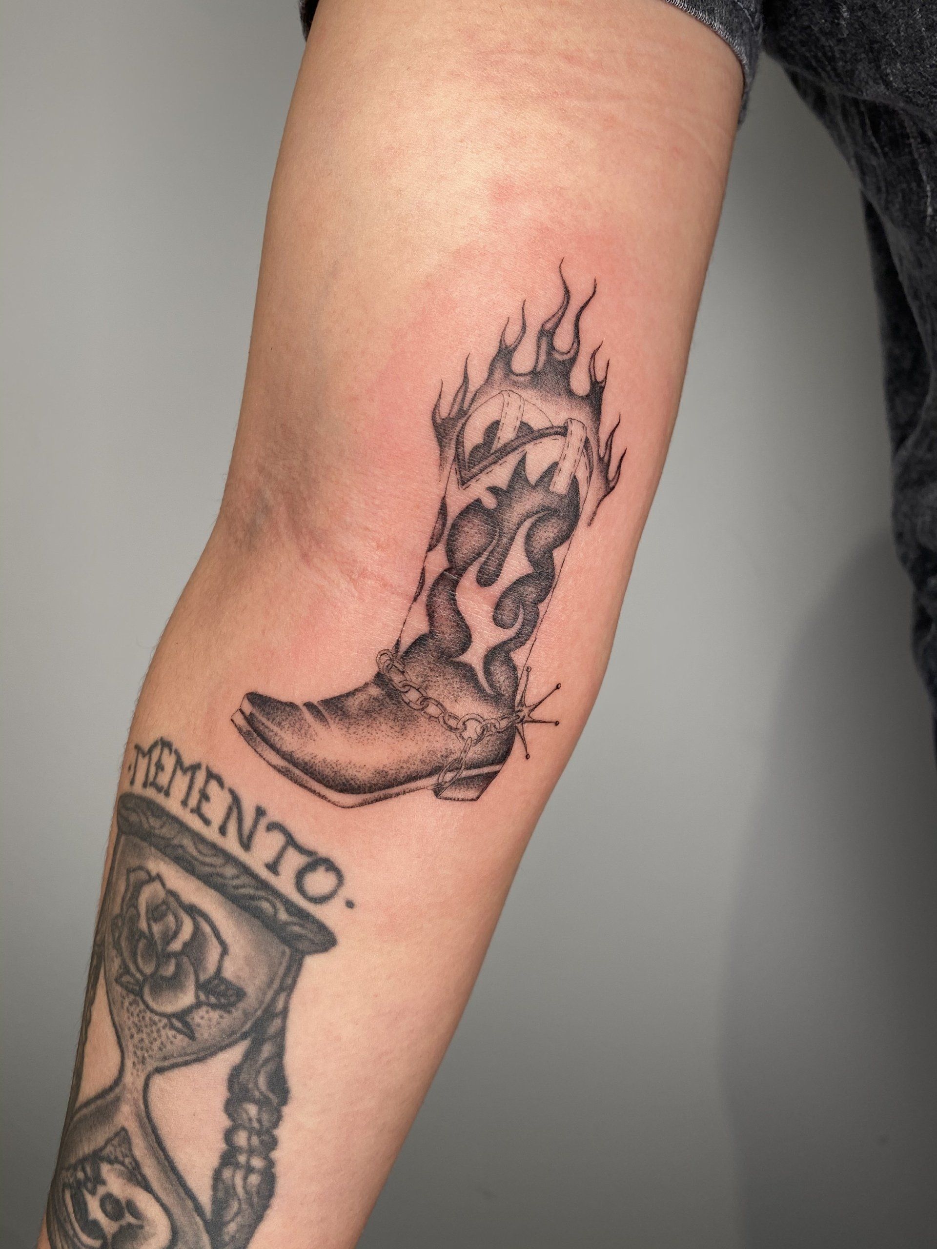 A person has a tattoo of a cowboy boot on their forearm.