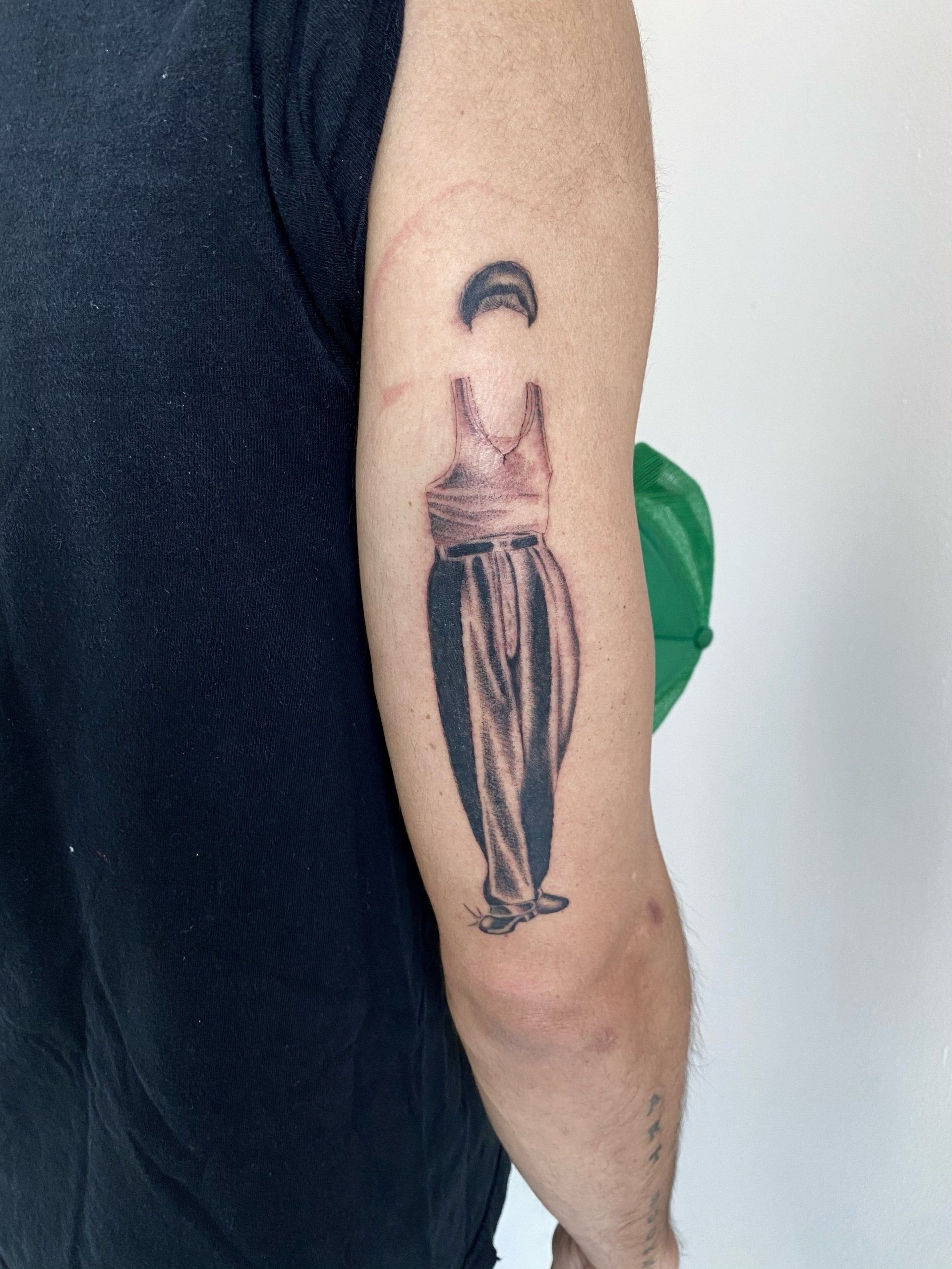 A man has a tattoo of a cholo on his arm.