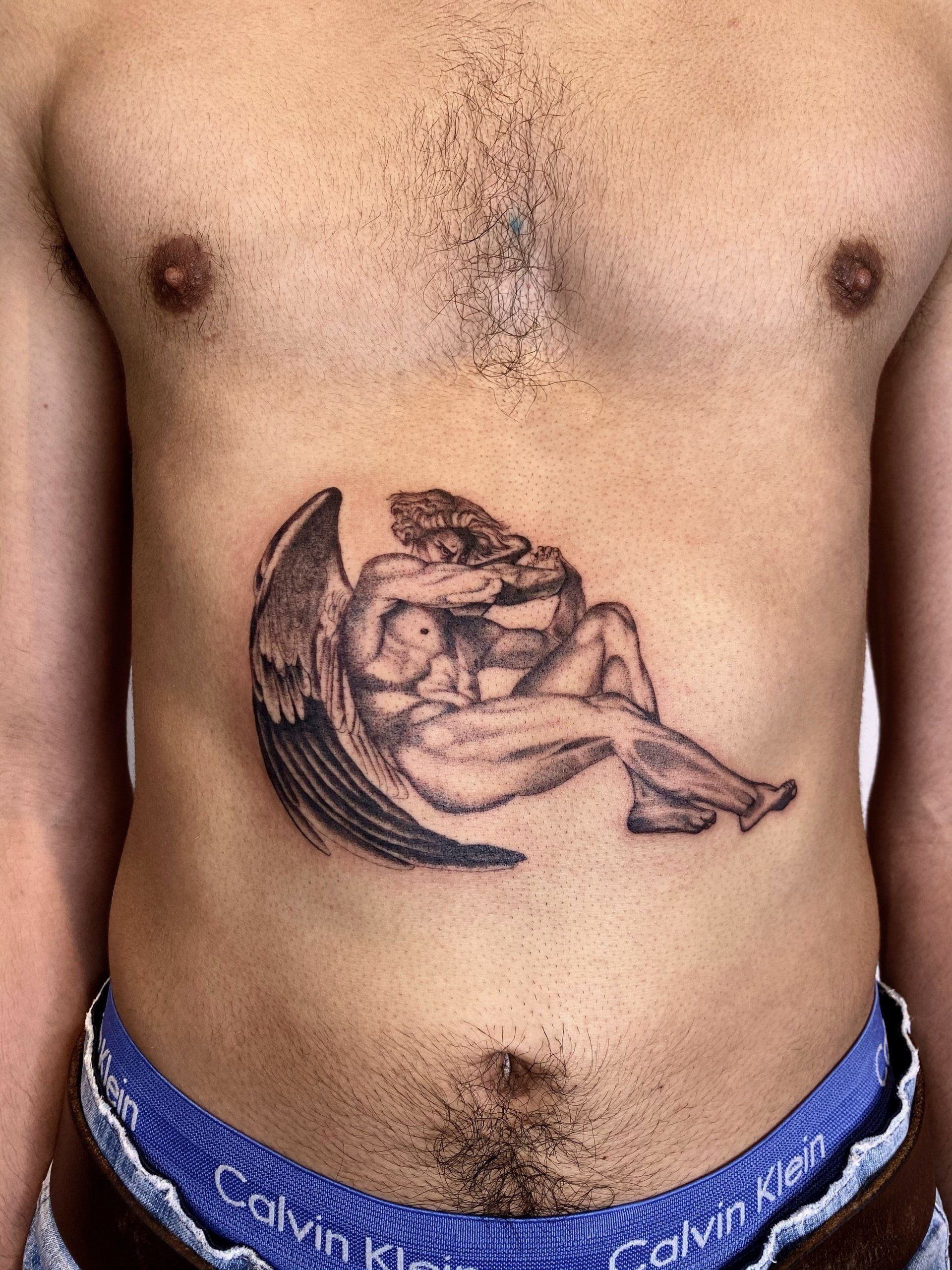 A man has a tattoo of an angel on his stomach.