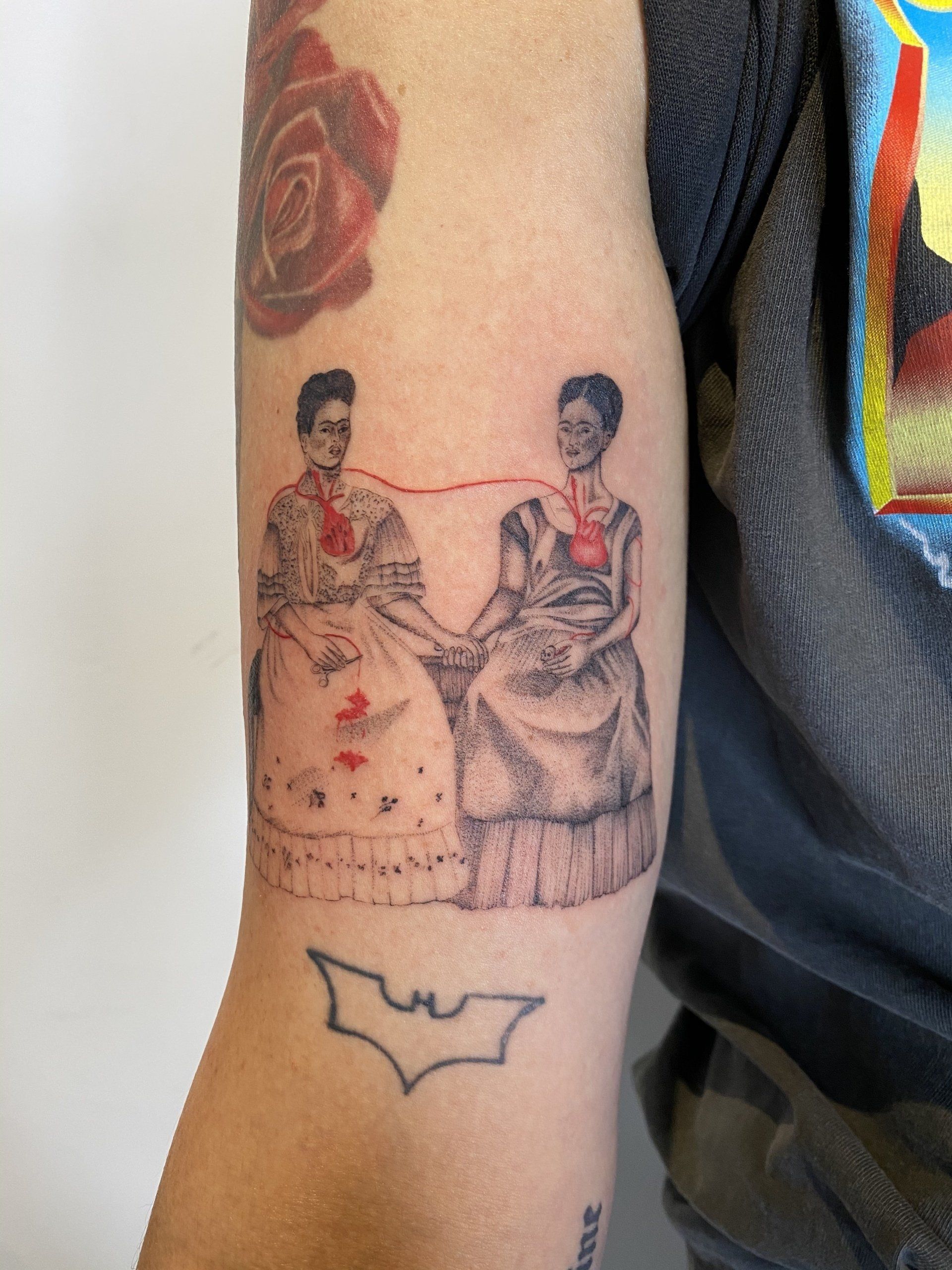 A person has a tattoo of two women holding hands on their arm.