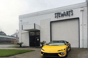 Yellow Lamborghini parked in front of Stewart's building with a large garage door.