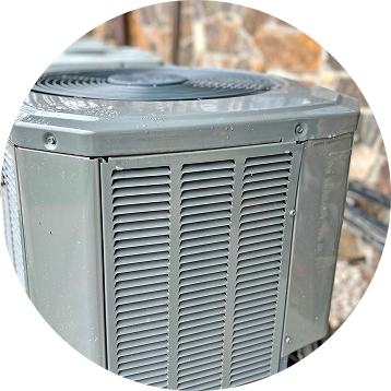 Gray air conditioning unit with a fan and louvered side panel, outdoors.