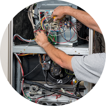 Person working on the electrical components of an HVAC system using a screwdriver.