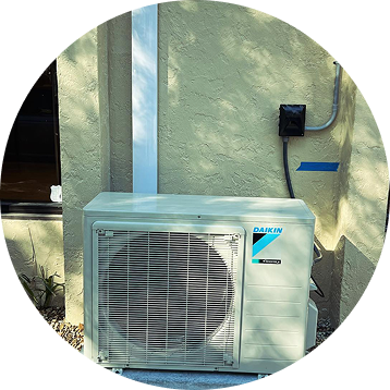 Daikin air conditioning unit mounted on a stucco wall. Metallic conduit and electrical box are visible.