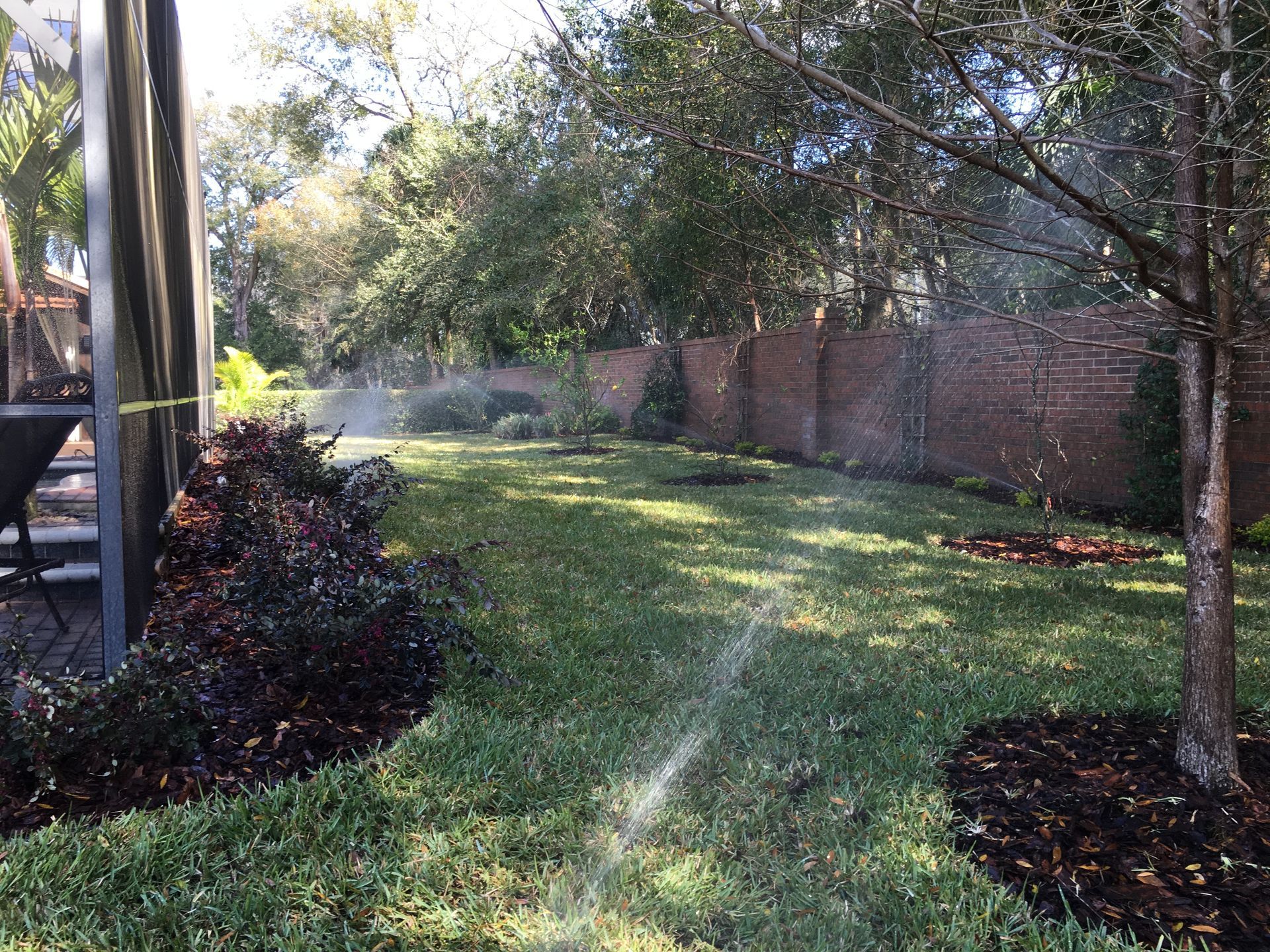 Lush garden with meticulously trimmed hedges, winding paths, and a variety of trees, set against a backdrop of green hills.