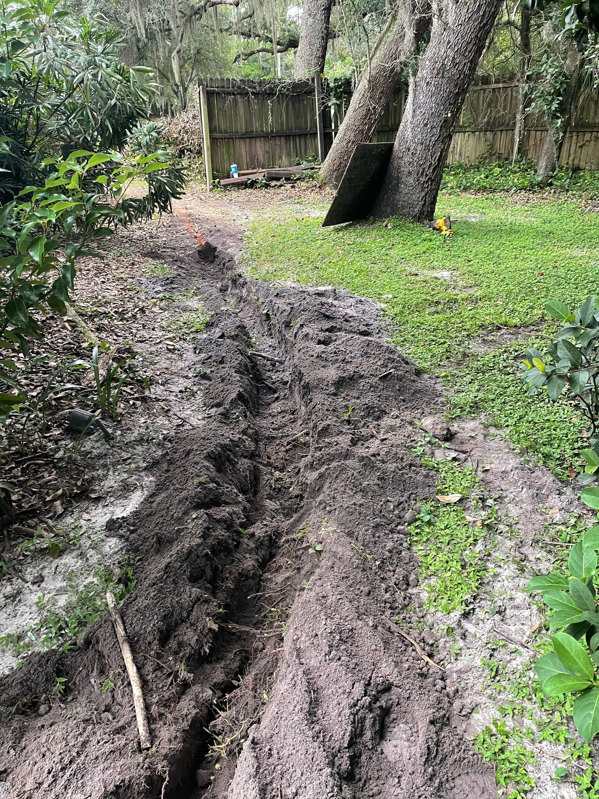 Brick-paved curved driveway with patterned border, next to green grass and hedge.