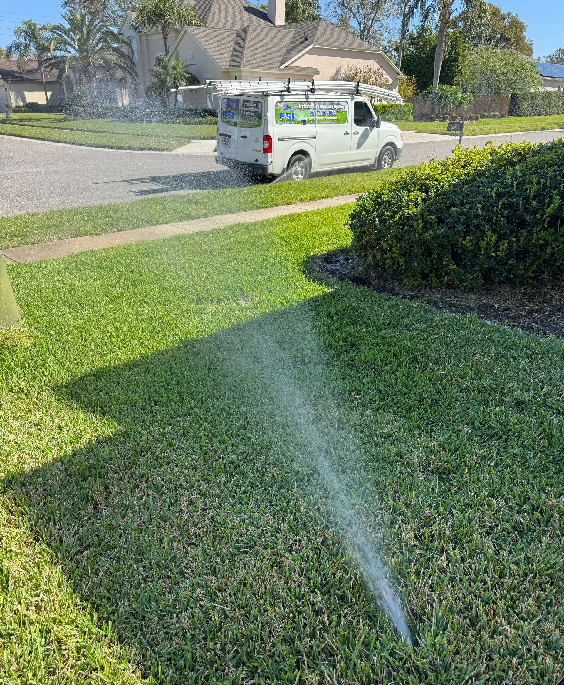 Person trimming a green hedge with a red and silver hedge trimmer.