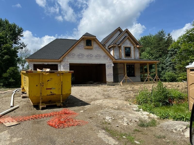 A house under construction with a yellow dumpster in front of it.