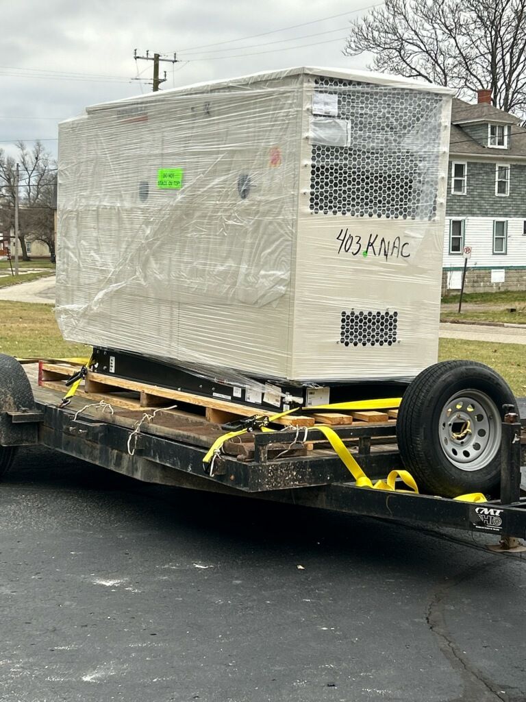 A trailer with a large box on it is parked on the side of the road.