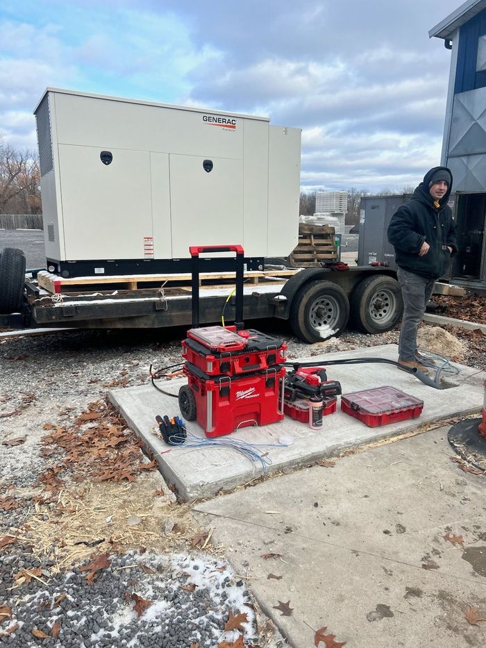 A man is standing next to a generator on a trailer.