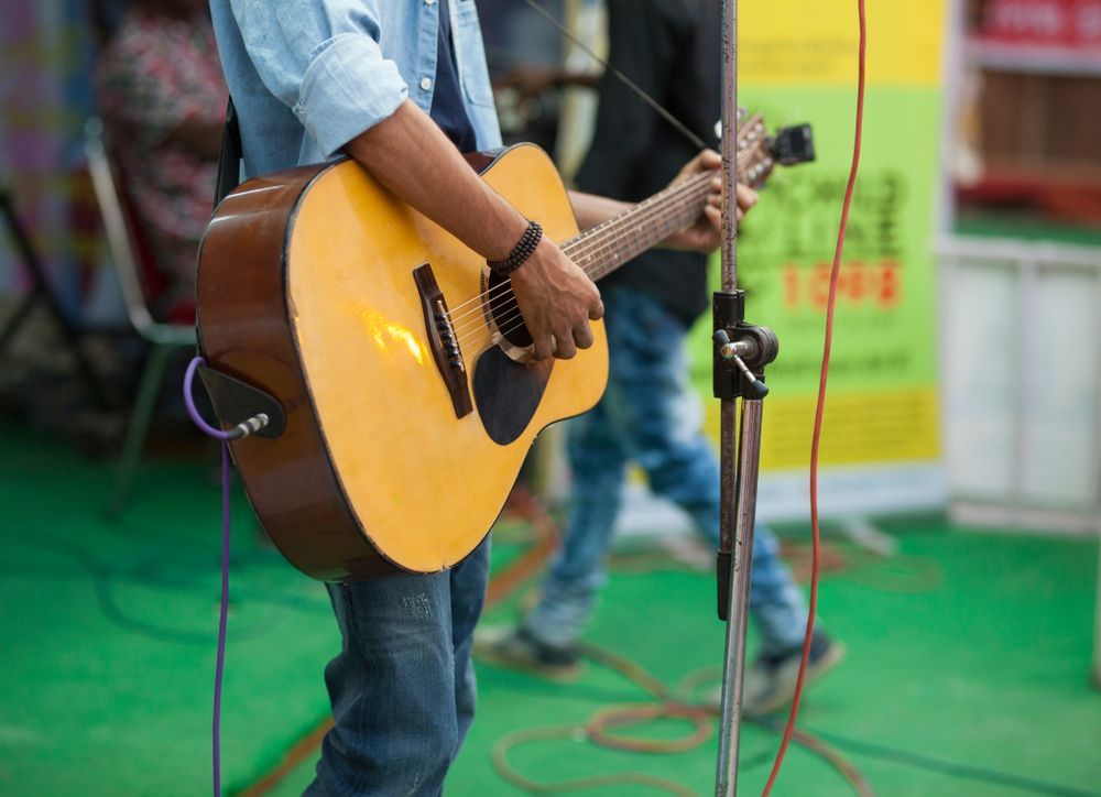 A Man is Playing an Acoustic Guitar in Front of a Microphone — Event Hire in Albury, NSW