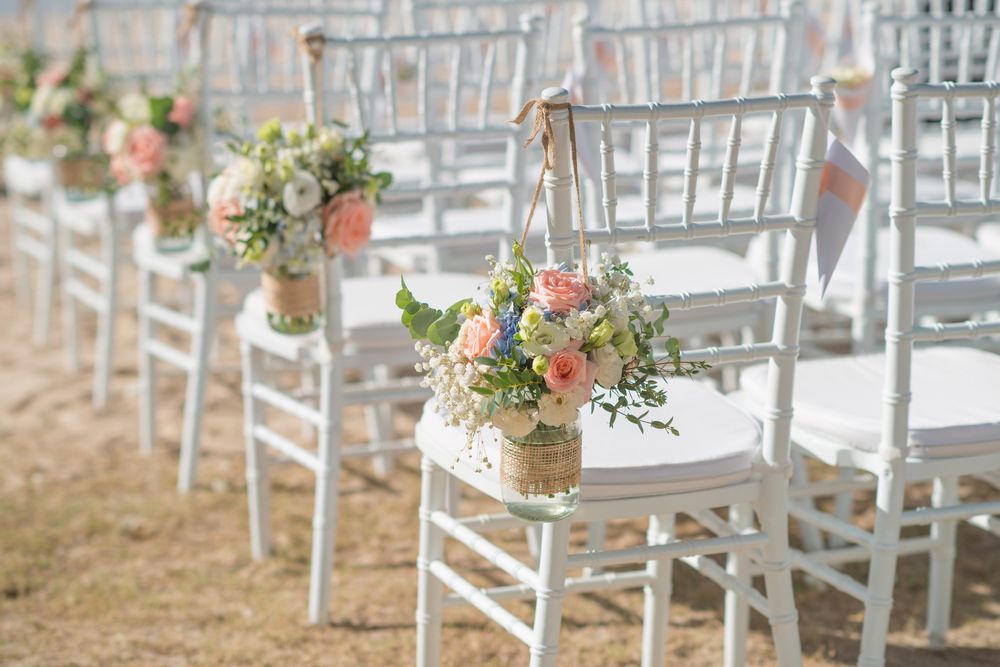 A Row of White Chairs Decorated With Flowers For a Wedding Ceremony — Event Hire in Wodonga, NSW