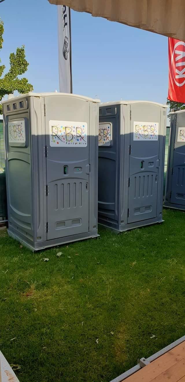 A Row of Portable Toilets Sitting on Top of a Lush Greenfield — Event Hire in Wodonga, NSW