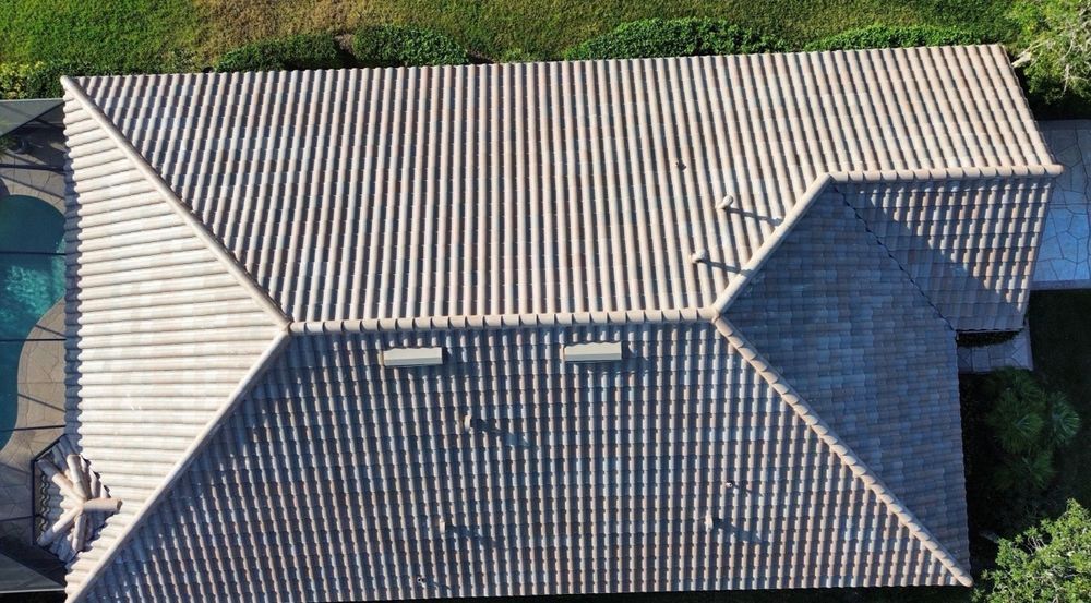 Aerial view of a beige tiled roof with skylights and a dark-blue roof section.