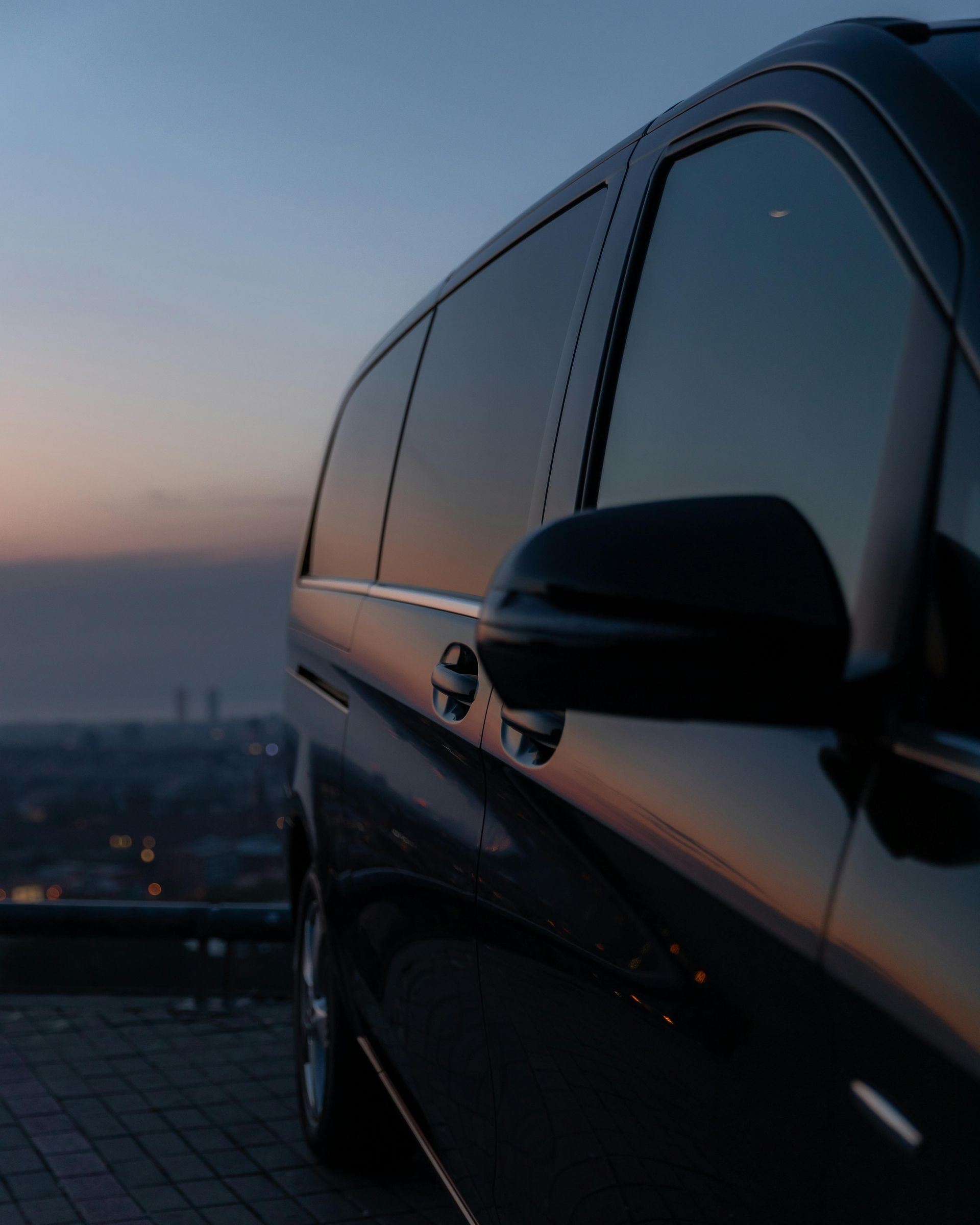 Black SUV parked at sunset, with city skyline blurred in the background.