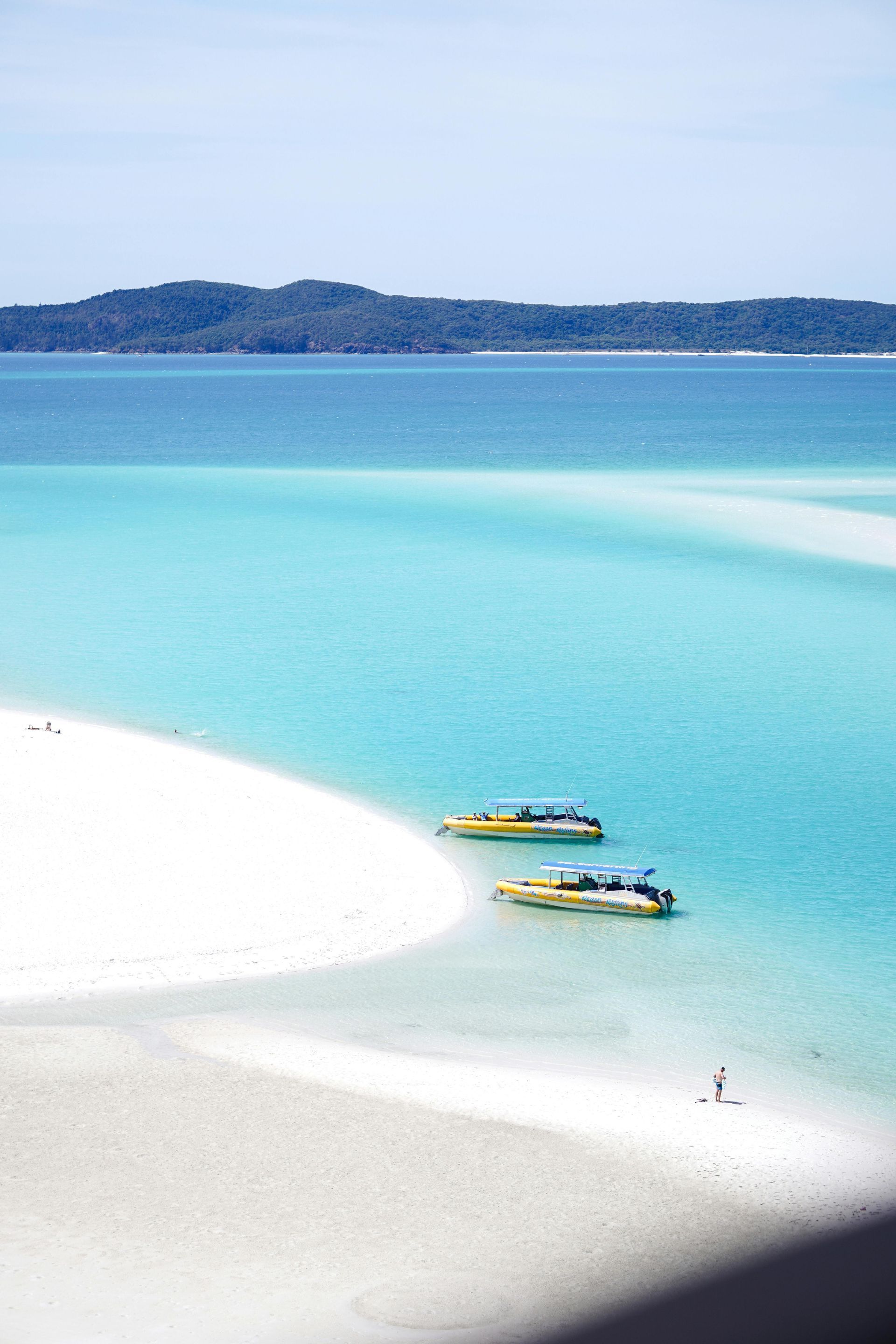 Turquoise tropical bay with white sand and two small boats near the shore