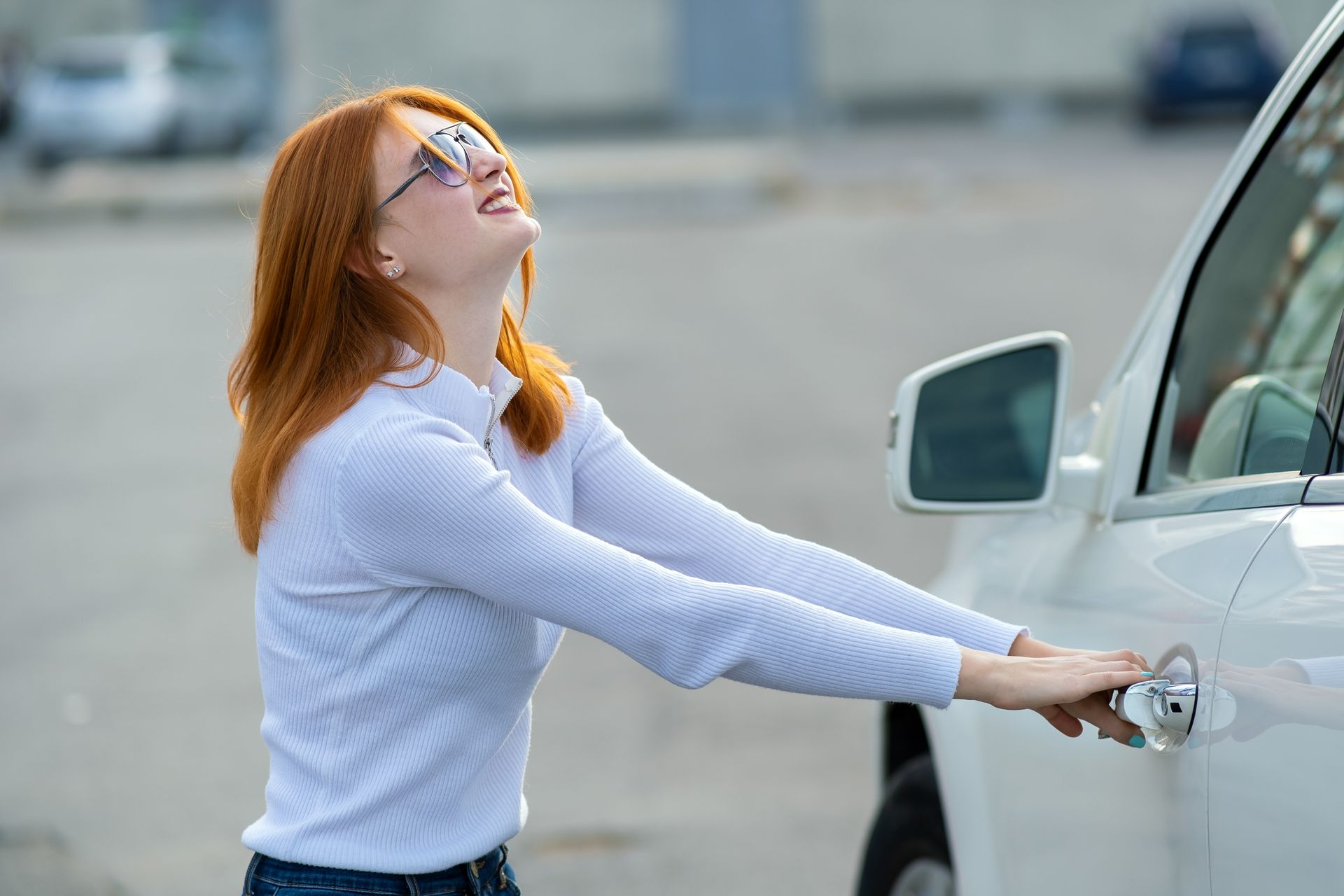 A woman is trying to open the door of her car.