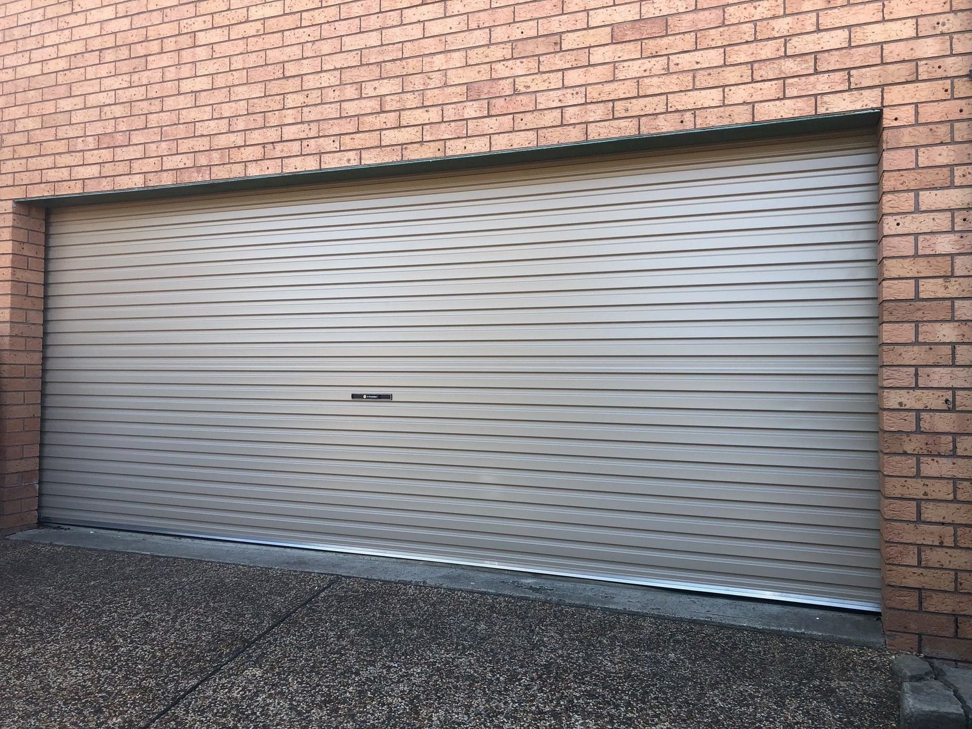 A garage door is sitting on the side of a brick building.