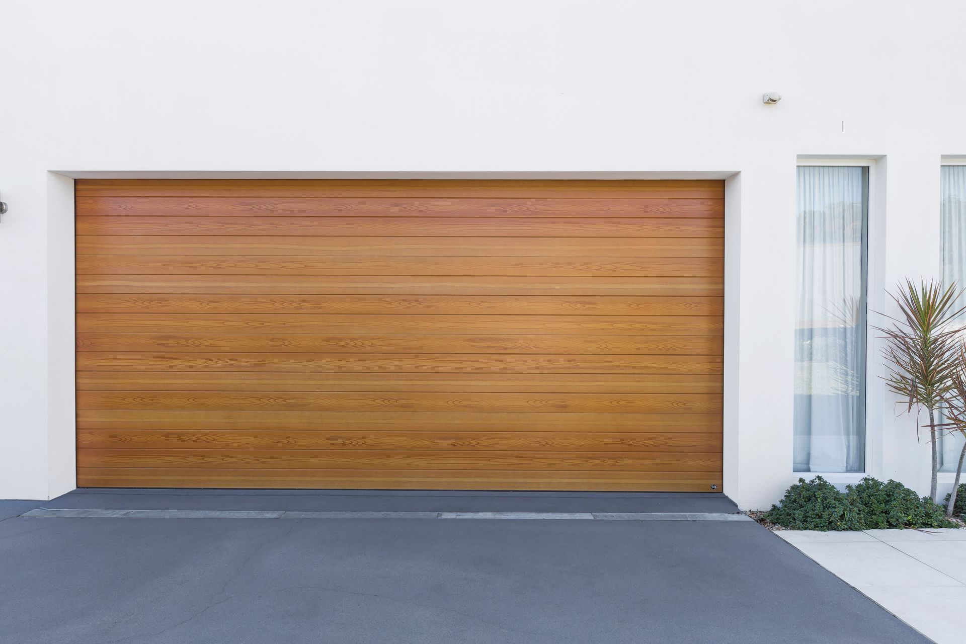 A white house with a wooden garage door and a driveway.