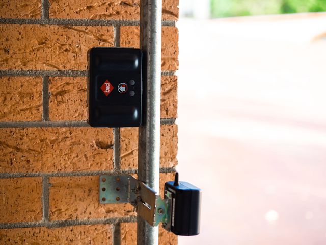 A black box is mounted on a brick wall next to a metal pipe.