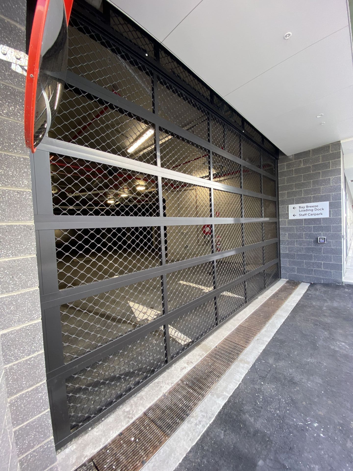 A parking garage with a large glass door and a mirror.