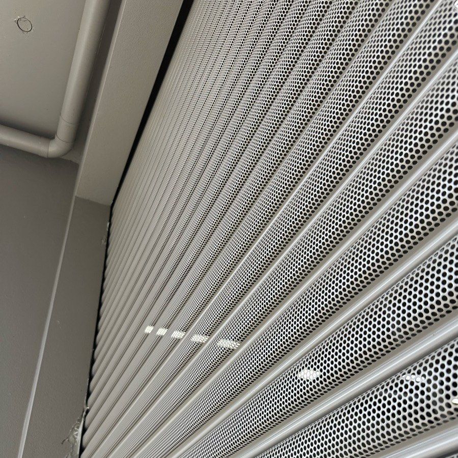 A close up of a perforated metal shutter on a building.