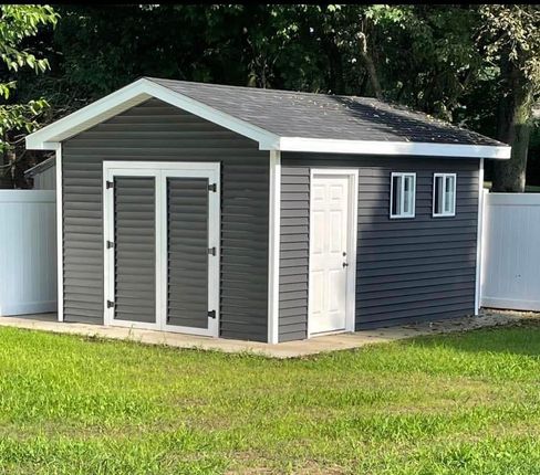 A small shed with a white fence in the background