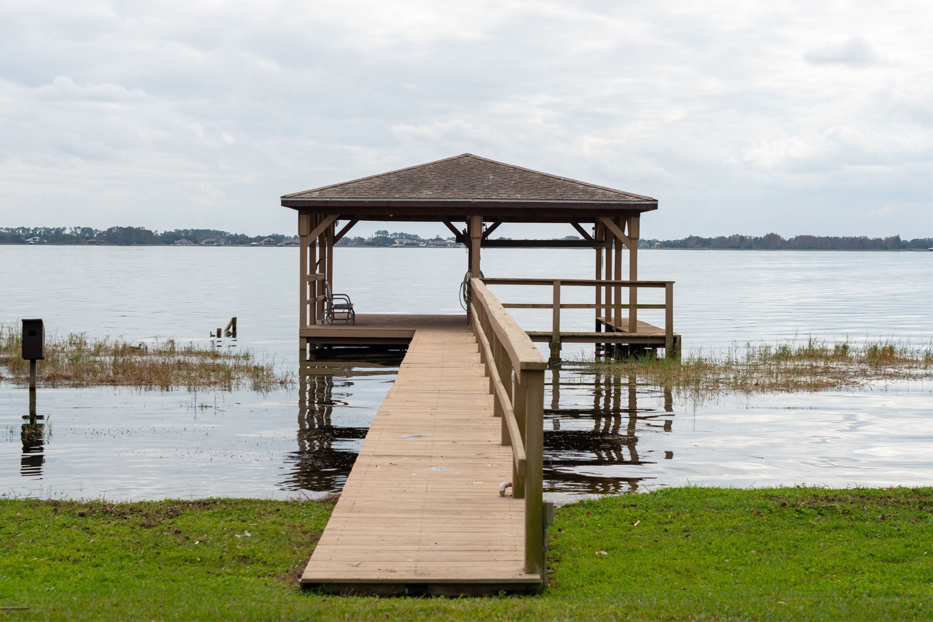 Wooden dock with gazebo over water on a cloudy day.