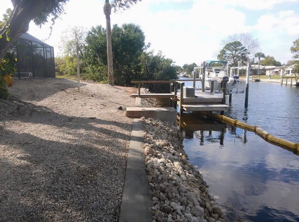 Waterfront property with a dock, retaining wall, and gravel path.