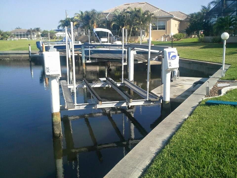 Boat lift in a canal; houses and palm trees in the background; sunny day.
