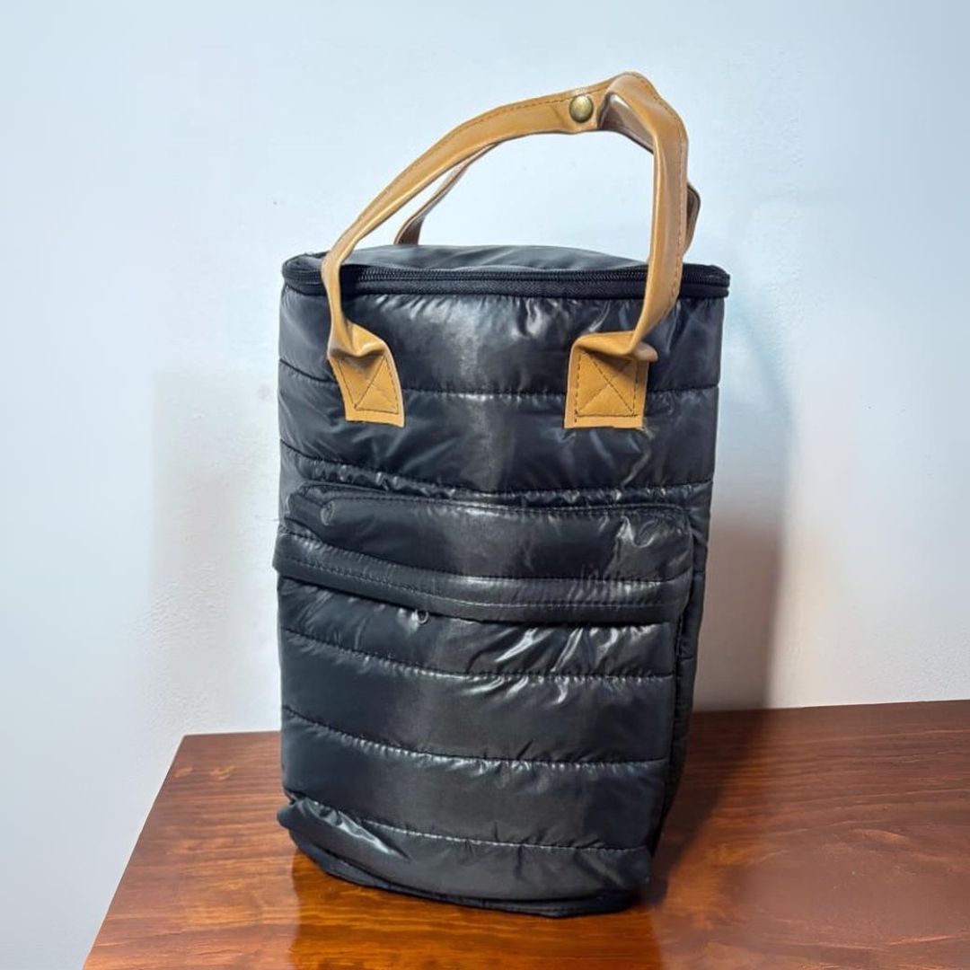 Bolsa enfriadora de vino con aislamiento negro, asa color tostado y detalles sobre una mesa de madera.