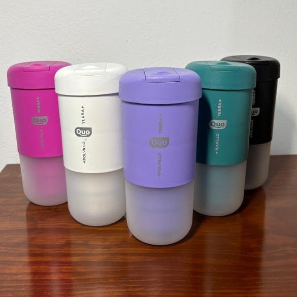 Cinco licuadoras de viaje coloridas en rosa, blanco, morado, verde azulado y negro, sobre una superficie de madera.