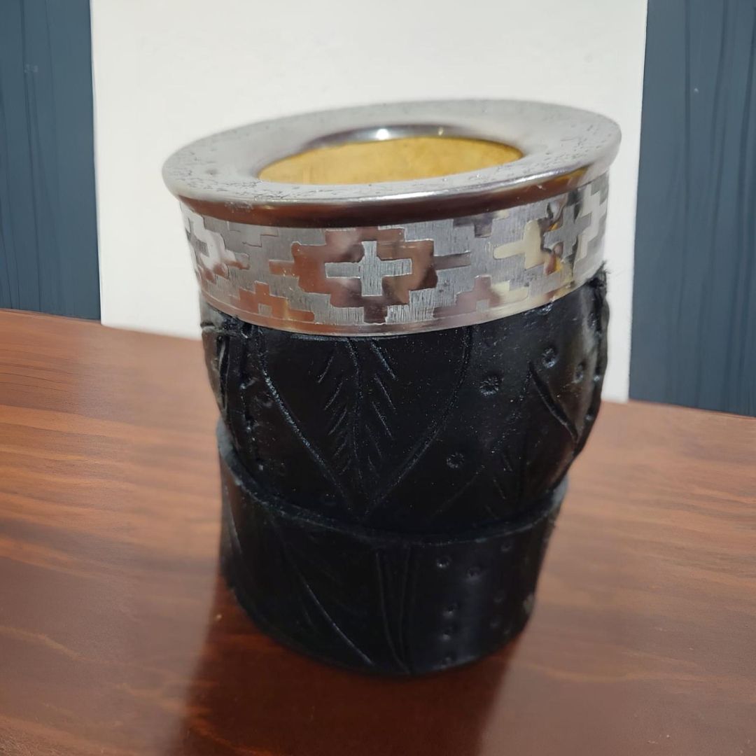 Mate negro con detalles plateados sobre mesa de madera.