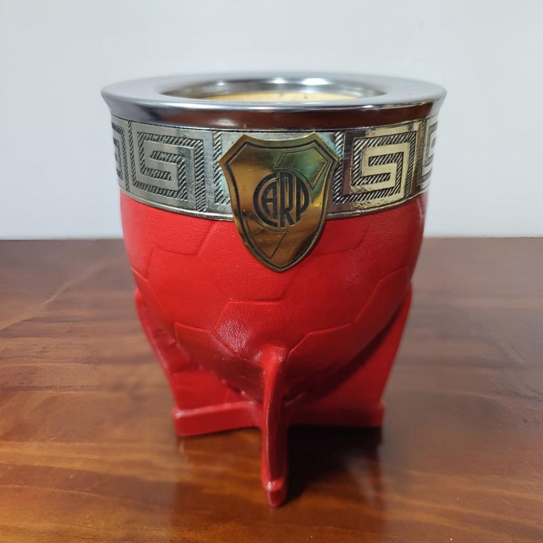 Mate rojo y plateado con el escudo de River Plate sobre mesa de madera.