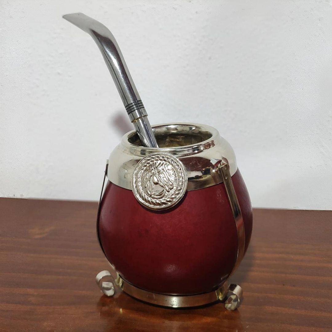 Mate rojo con detalles plateados y pajita sobre superficie de madera.