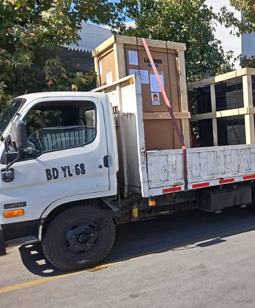 Un camión blanco con cajas en la parte trasera está estacionado al costado de la carretera.