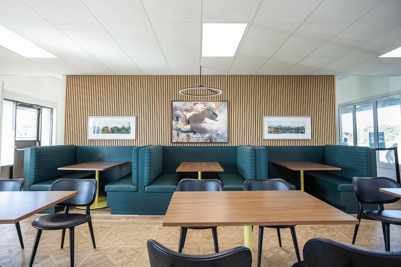 A thoughtfully designed commercial dining space featuring a row of comfortable booths along a wall, serving as an elevated restaurant or corporate gathering area.