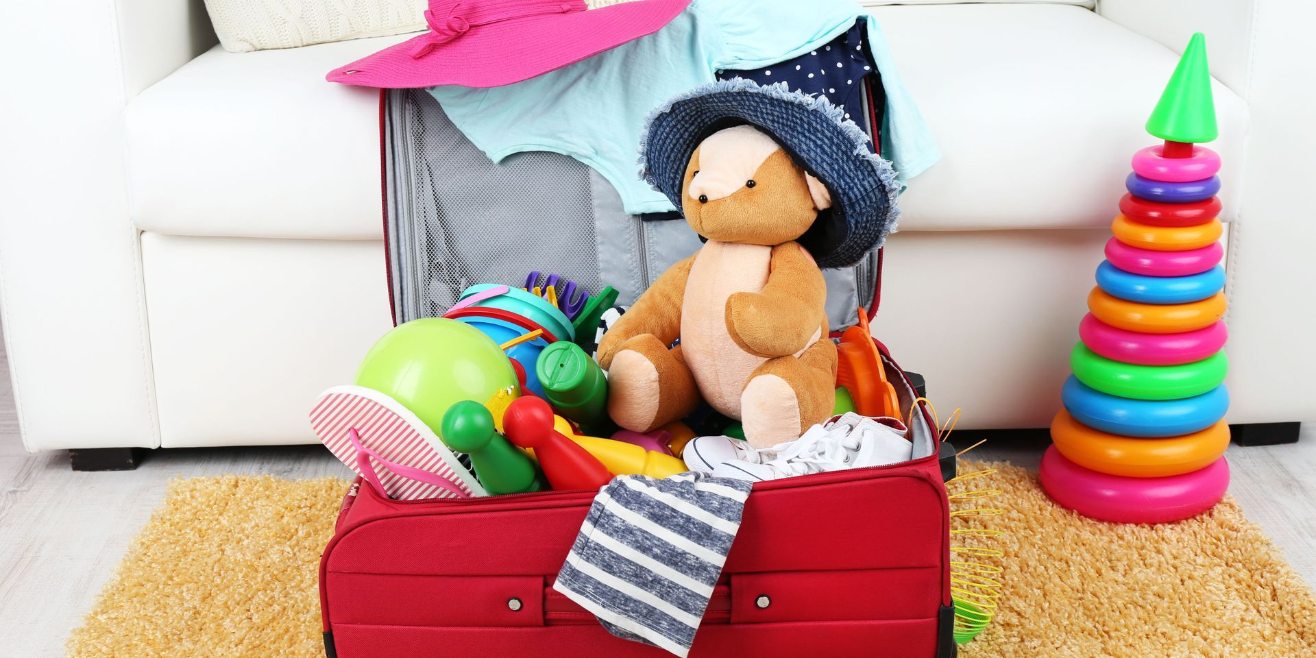 A red suitcase filled with toys and clothes in a living room.
