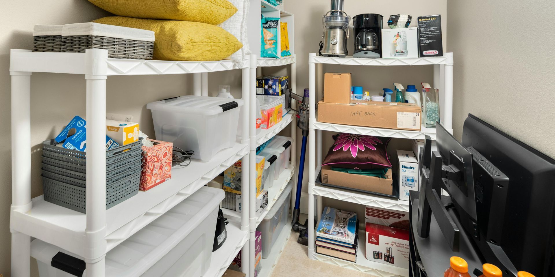 A room filled with shelves , bins , and a television.