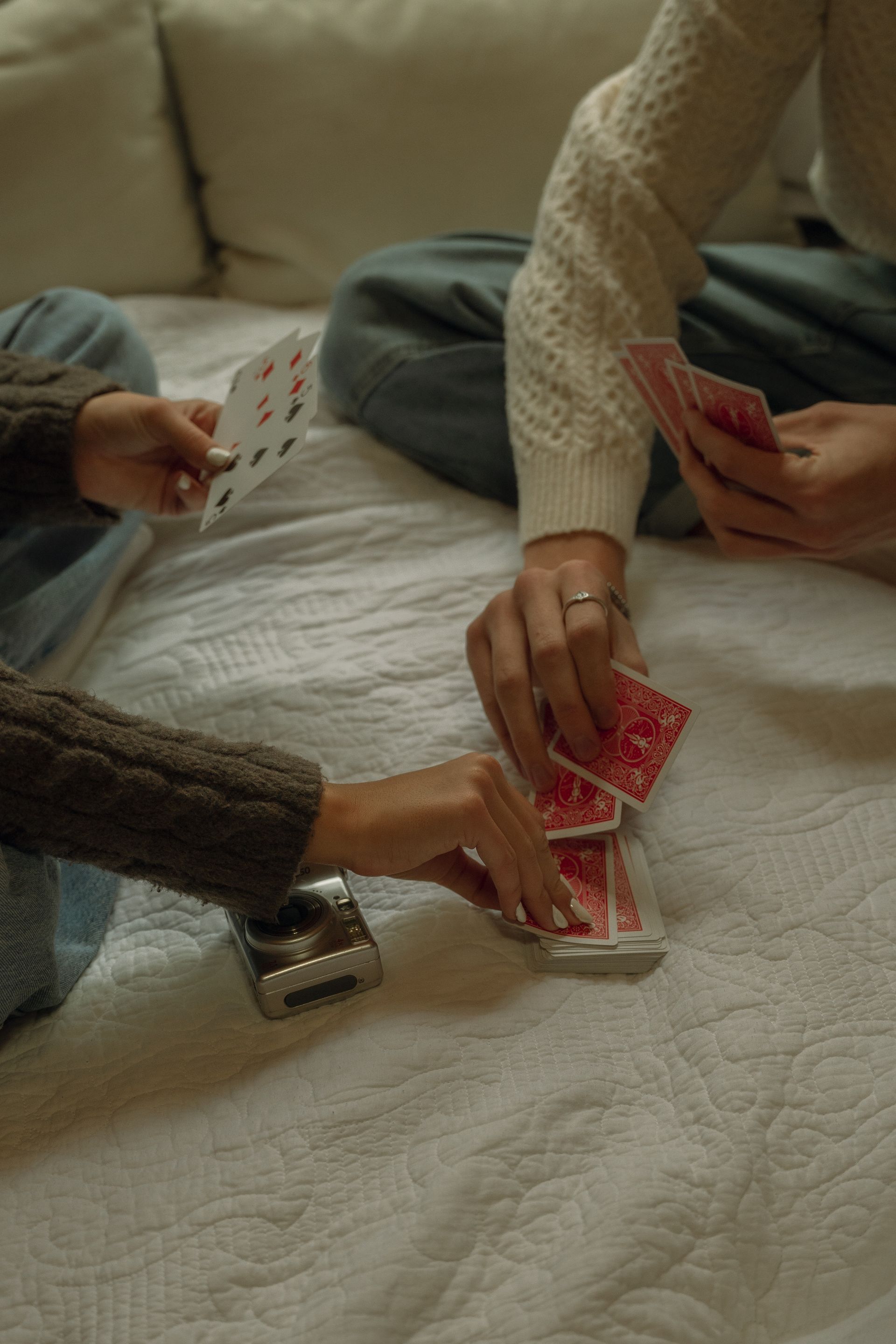 A group of people are playing cards on a bed.