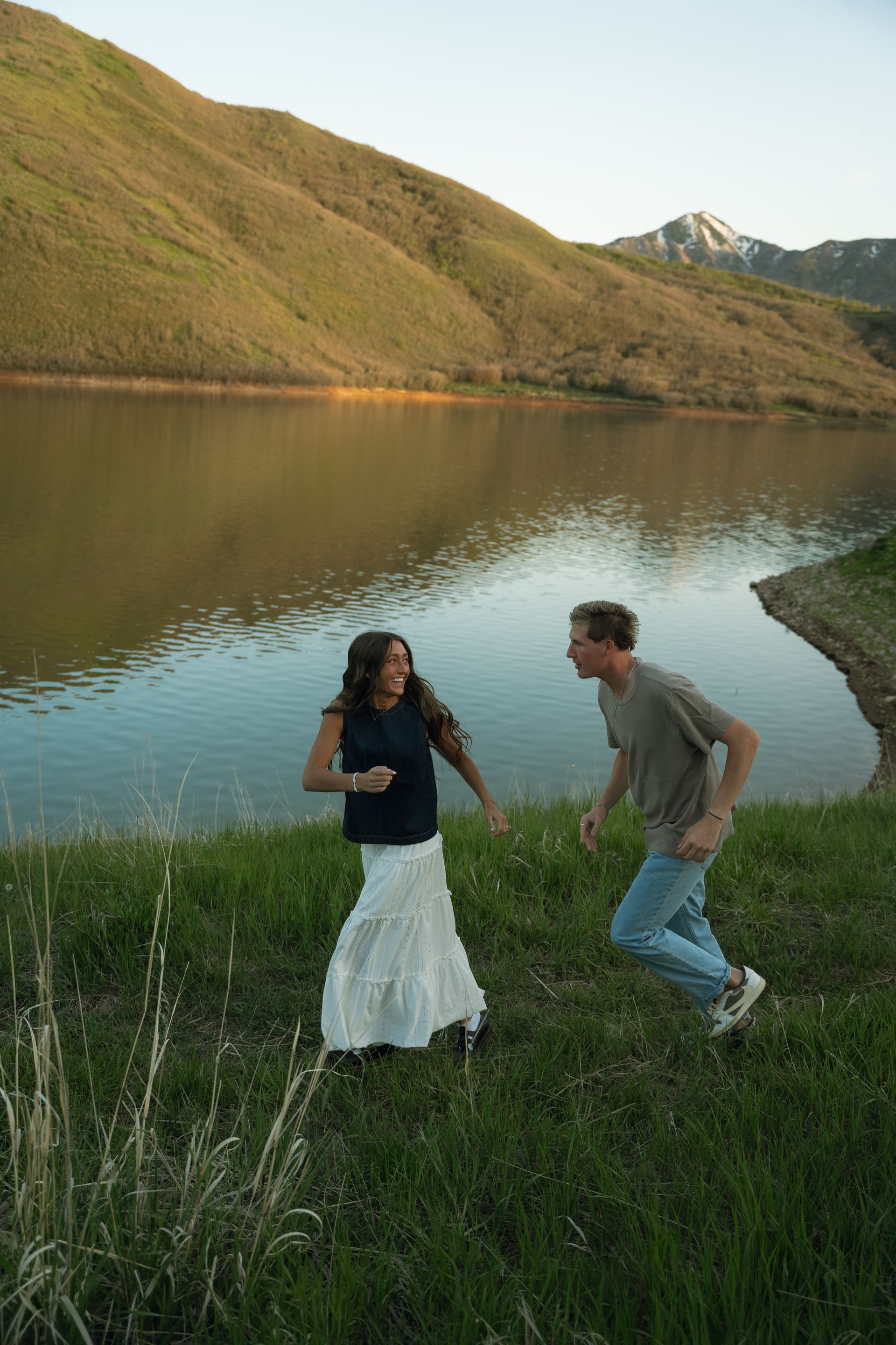 A man and a woman are standing next to a lake.