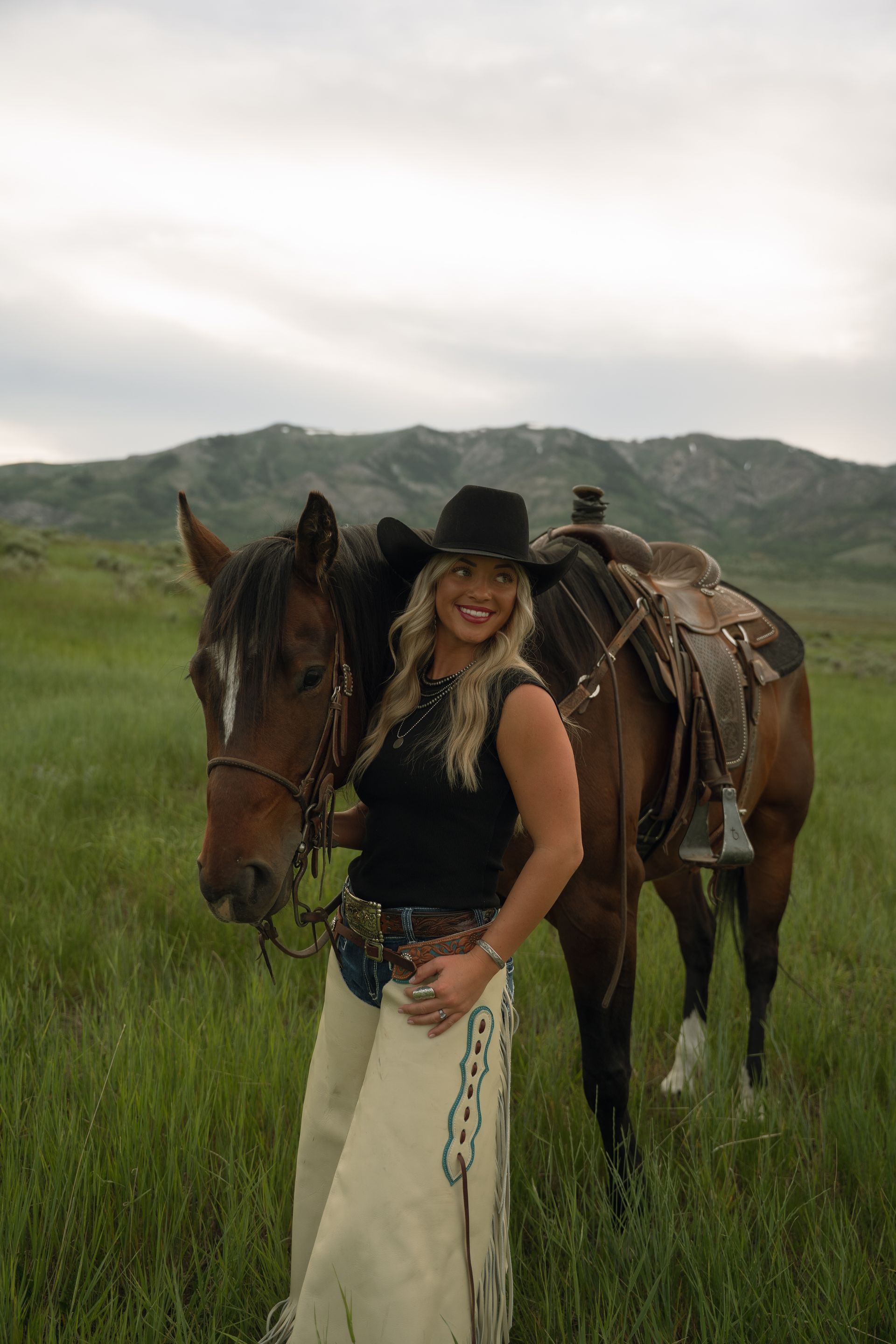 A woman is standing next to a horse in a field.
